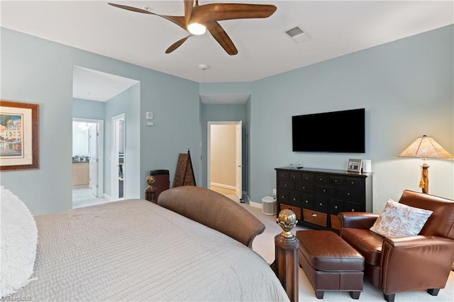 bedroom with ceiling fan, light colored carpet, and ensuite bathroom