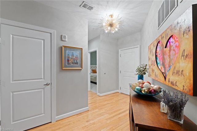 hallway with light hardwood / wood-style flooring and a chandelier