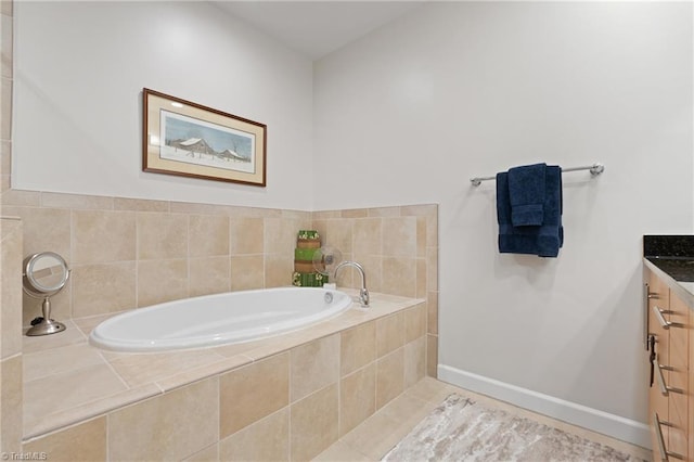 bathroom with a relaxing tiled tub, vanity, and tile patterned floors