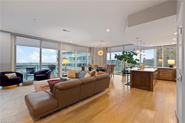 living room featuring light hardwood / wood-style flooring, expansive windows, and a notable chandelier