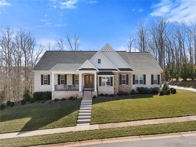 view of front of property with covered porch, roof with shingles, a front lawn, and brick siding