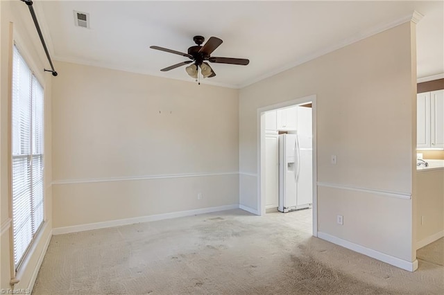 carpeted spare room featuring crown molding and ceiling fan