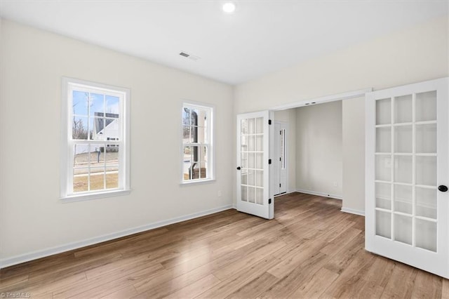 spare room with light hardwood / wood-style floors, french doors, and a healthy amount of sunlight