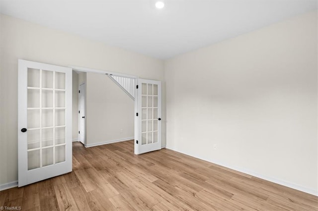 empty room with light hardwood / wood-style floors and french doors