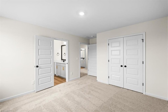 unfurnished bedroom with light colored carpet, ensuite bath, and a closet