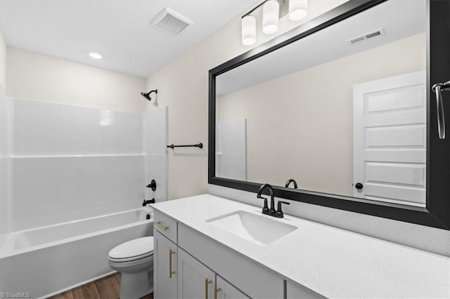 full bathroom featuring hardwood / wood-style flooring, washtub / shower combination, vanity, and toilet