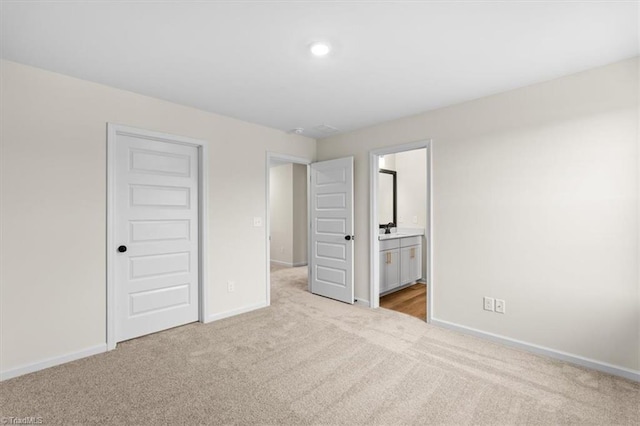 unfurnished bedroom featuring ensuite bathroom, light carpet, and a closet