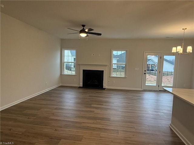 unfurnished living room with dark hardwood / wood-style floors and ceiling fan with notable chandelier