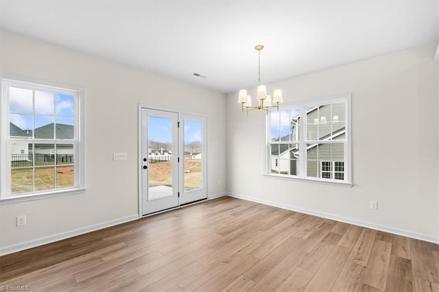 unfurnished dining area with an inviting chandelier and light hardwood / wood-style flooring