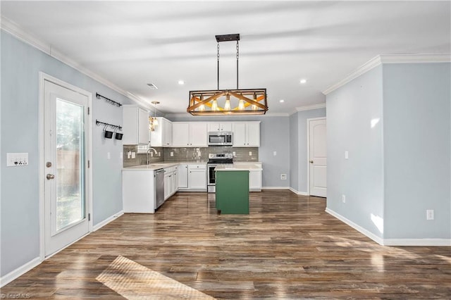 kitchen with pendant lighting, white cabinets, ornamental molding, a kitchen island, and stainless steel appliances