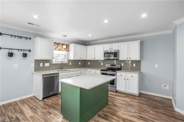 kitchen with white cabinets, a kitchen island, decorative light fixtures, stainless steel appliances, and sink