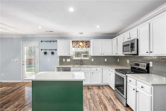 kitchen with hardwood / wood-style floors, decorative light fixtures, white cabinetry, stainless steel appliances, and sink