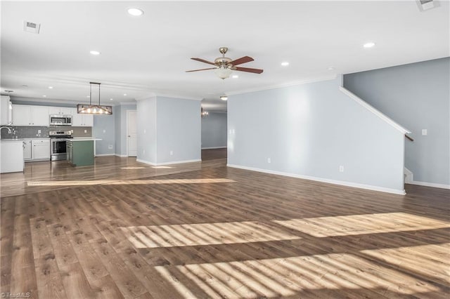 unfurnished living room featuring sink, ceiling fan with notable chandelier, ornamental molding, and dark hardwood / wood-style flooring