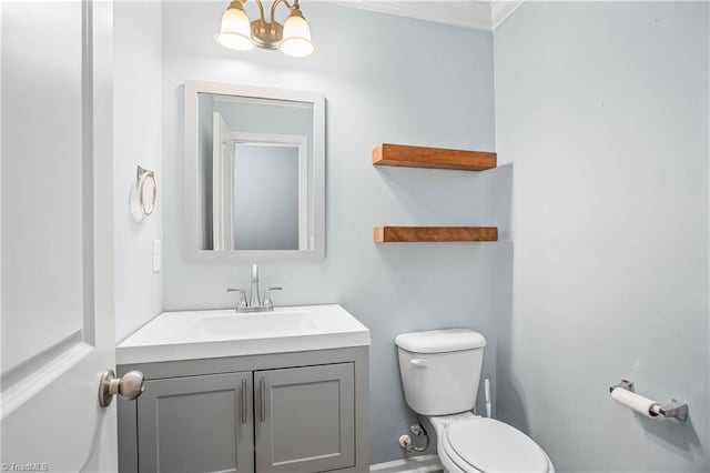 bathroom with toilet, vanity, ornamental molding, and a chandelier