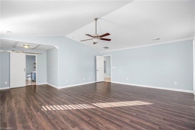 spare room featuring lofted ceiling, dark wood-type flooring, ornamental molding, ceiling fan, and a barn door