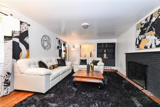 living room featuring wood-type flooring, a brick fireplace, and crown molding