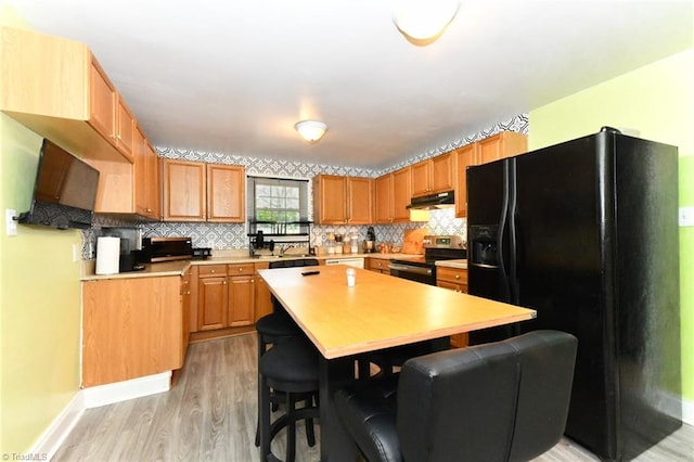 kitchen with backsplash, black fridge with ice dispenser, a kitchen island, light hardwood / wood-style flooring, and electric range