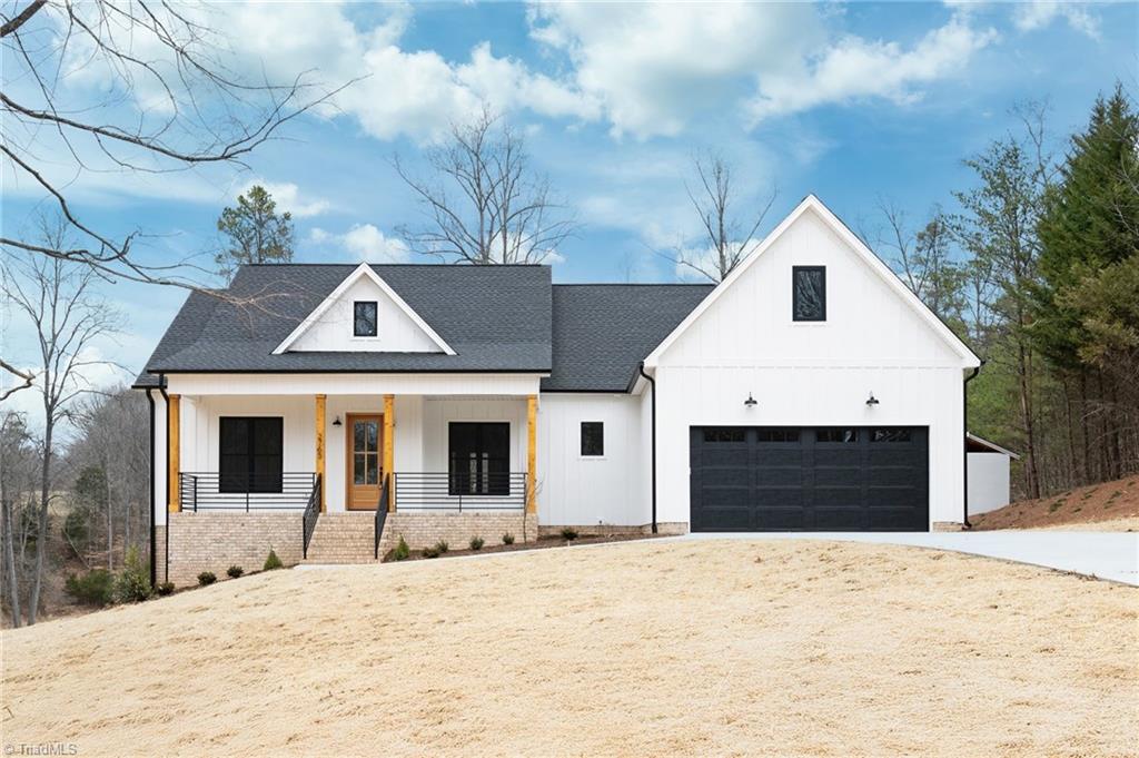 modern farmhouse style home featuring covered porch, a garage, a shingled roof, concrete driveway, and board and batten siding