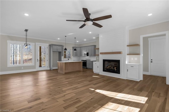 unfurnished living room with recessed lighting, crown molding, baseboards, and wood finished floors