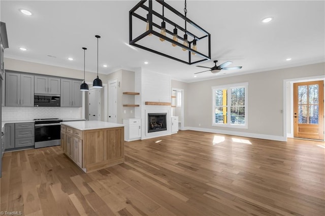 kitchen with light wood-style flooring, a large fireplace, electric stove, ornamental molding, and gray cabinets