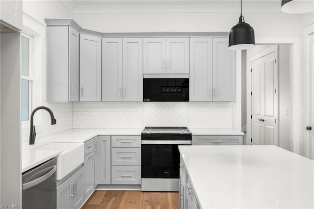 kitchen with stainless steel appliances, light countertops, crown molding, and a sink