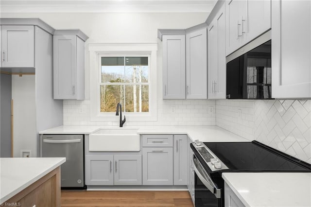 kitchen featuring light countertops, gray cabinetry, electric range oven, a sink, and dishwasher