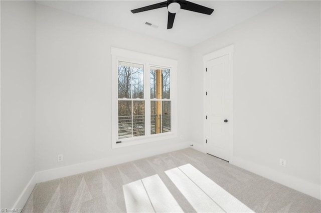 carpeted spare room with visible vents, ceiling fan, and baseboards