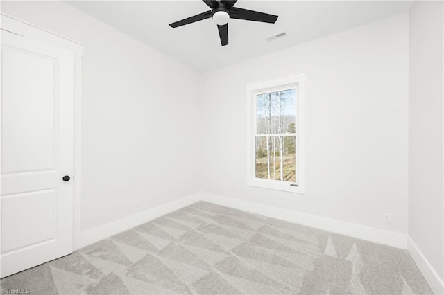 empty room featuring a ceiling fan, light colored carpet, visible vents, and baseboards