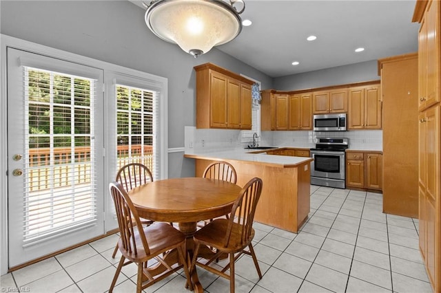 kitchen featuring sink, tasteful backsplash, kitchen peninsula, light tile patterned flooring, and appliances with stainless steel finishes