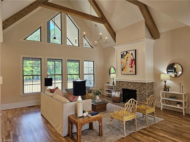 living room featuring hardwood / wood-style floors, high vaulted ceiling, an inviting chandelier, a brick fireplace, and beamed ceiling