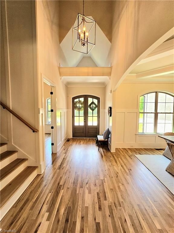 foyer with a chandelier, french doors, high vaulted ceiling, and hardwood / wood-style floors