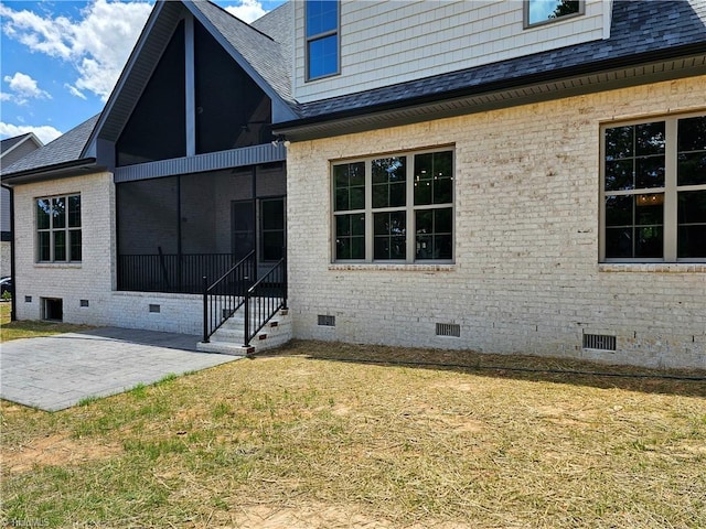 rear view of property with a sunroom, a yard, and a patio