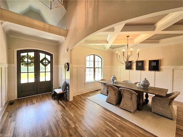 foyer entrance with an inviting chandelier, coffered ceiling, french doors, dark hardwood / wood-style floors, and beamed ceiling