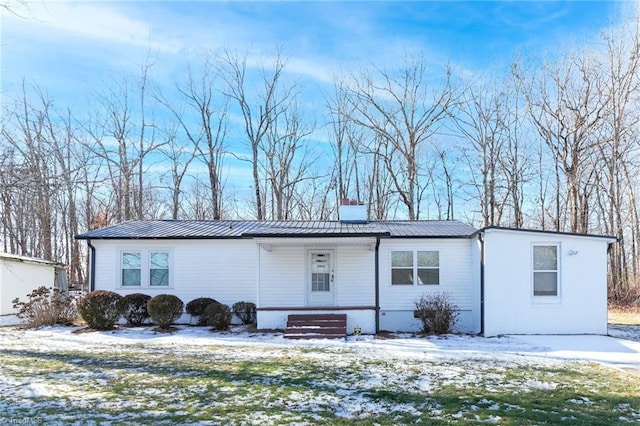 manufactured / mobile home with metal roof, a porch, and a chimney