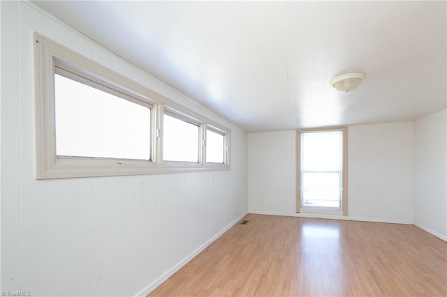 unfurnished room featuring light wood-style floors, visible vents, and baseboards