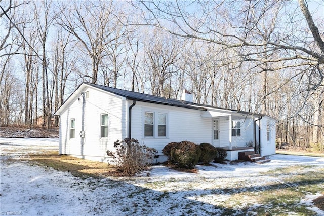 snow covered property featuring crawl space and a chimney