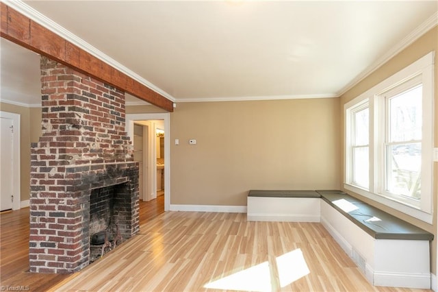 unfurnished living room featuring baseboards, a brick fireplace, wood finished floors, and crown molding