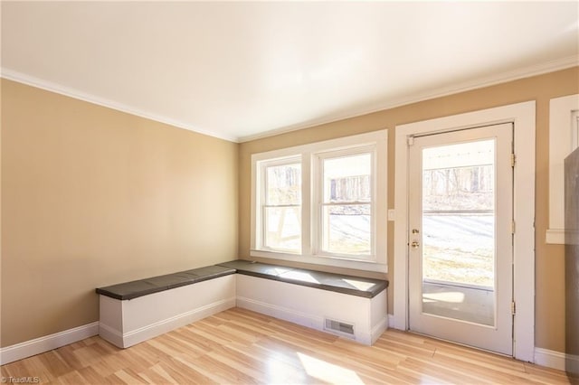 entryway with baseboards, crown molding, visible vents, and light wood-style floors