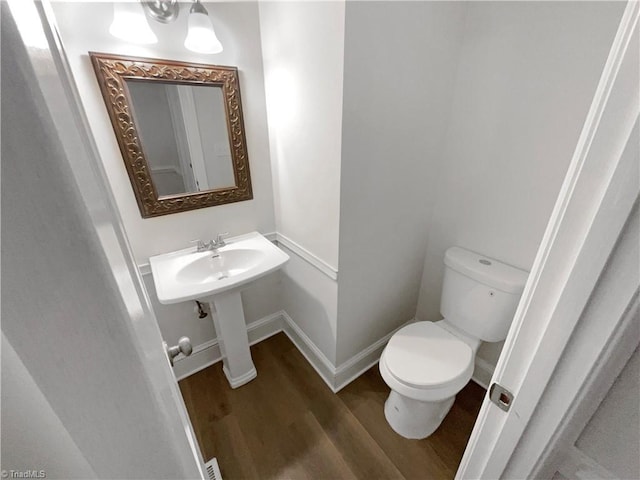 5605 Southstone Dr, Greensboro, NC 27406 - half bath featuring wood finished floors, toilet, baseboards, and a sink