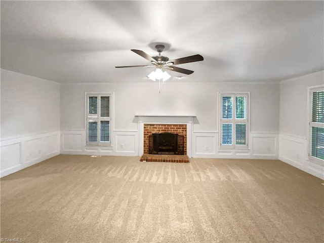 5605 Southstone Dr, Greensboro, NC 27406 - unfurnished living room with a decorative wall, light carpet, ceiling fan, a brick fireplace, and wainscoting