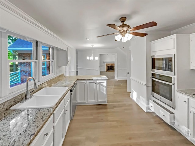 5605 Southstone Dr, Greensboro, NC 27406 - kitchen featuring appliances with stainless steel finishes, a sink, ceiling fan, white cabinetry, and a peninsula