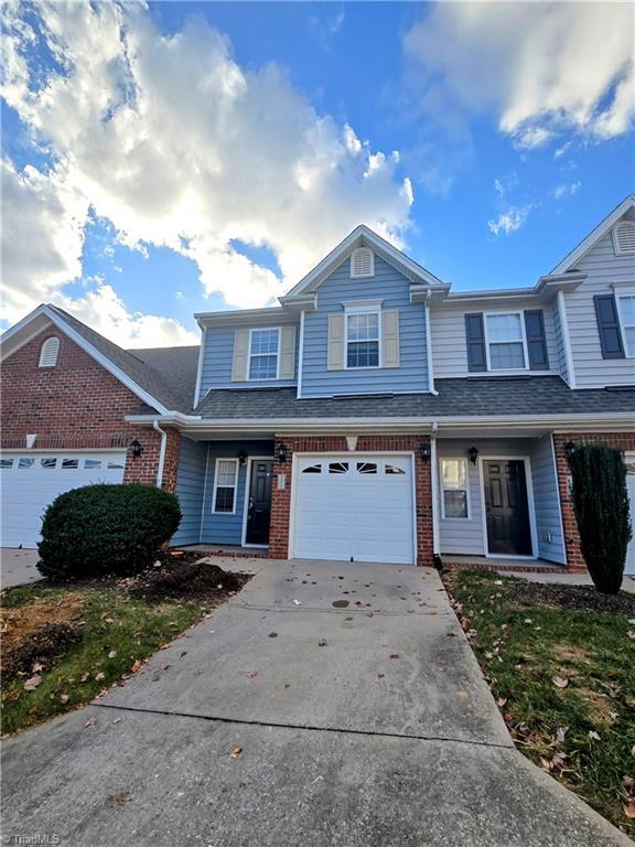 4472 Piedmont Trace Dr, Greensboro, NC 27409 - multi unit property featuring covered porch, driveway, roof with shingles, a garage, and brick siding