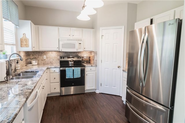 kitchen with appliances with stainless steel finishes, a sink, white cabinetry, dark wood finished floors, and light stone countertops