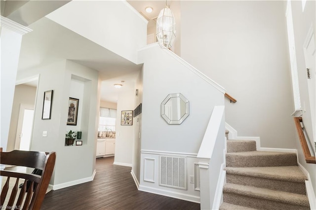staircase with wood finished floors, baseboards, and a high ceiling