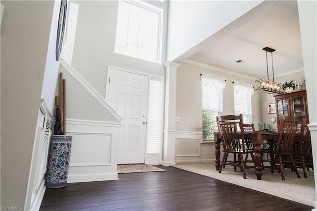 foyer entrance with wood finished floors, crown molding, and a chandelier