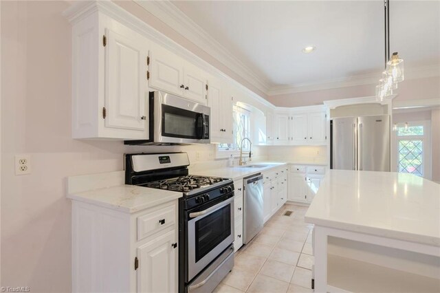kitchen featuring stainless steel appliances, a sink, white cabinetry, decorative light fixtures, and ornamental molding