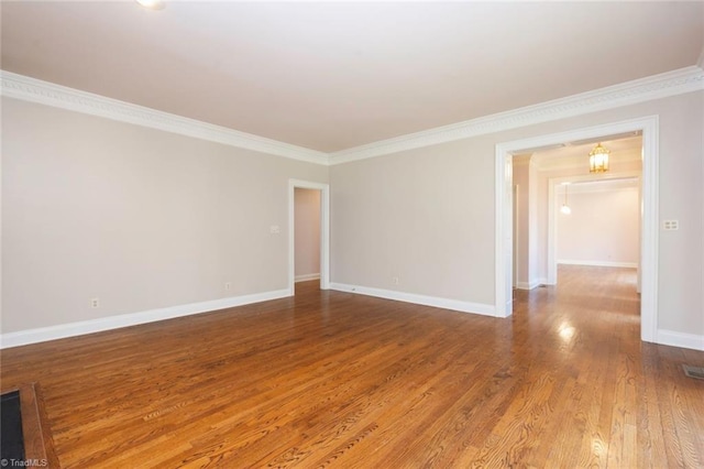 unfurnished room featuring wood finished floors, crown molding, and baseboards