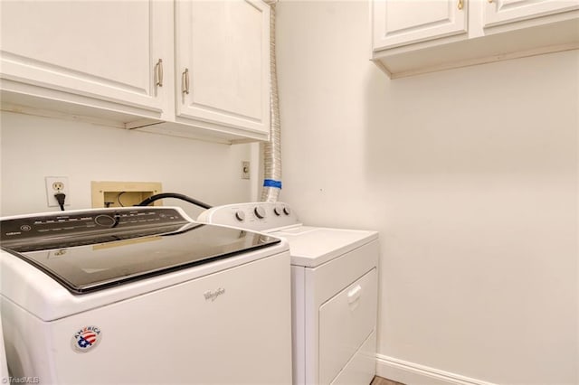 washroom featuring washing machine and dryer, baseboards, and cabinet space