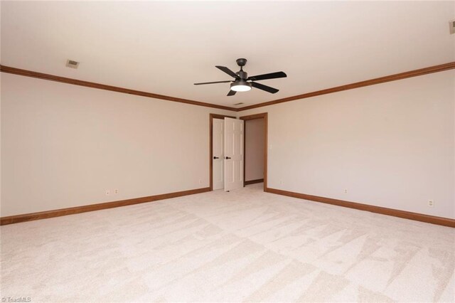 empty room featuring light carpet, baseboards, ceiling fan, and crown molding