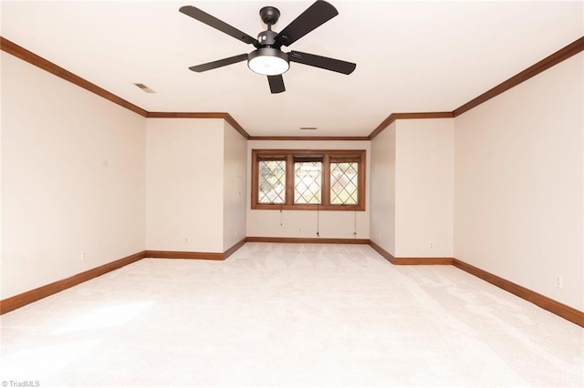 spare room with baseboards, visible vents, light colored carpet, ceiling fan, and crown molding